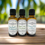 Three small dark glass bottles with white labels, containing different aroma oils. The labels indicate 'Sea Salt + Sandalwood', 'Agave Lime + Driftwood', and 'Ocean Mist + Moss'.